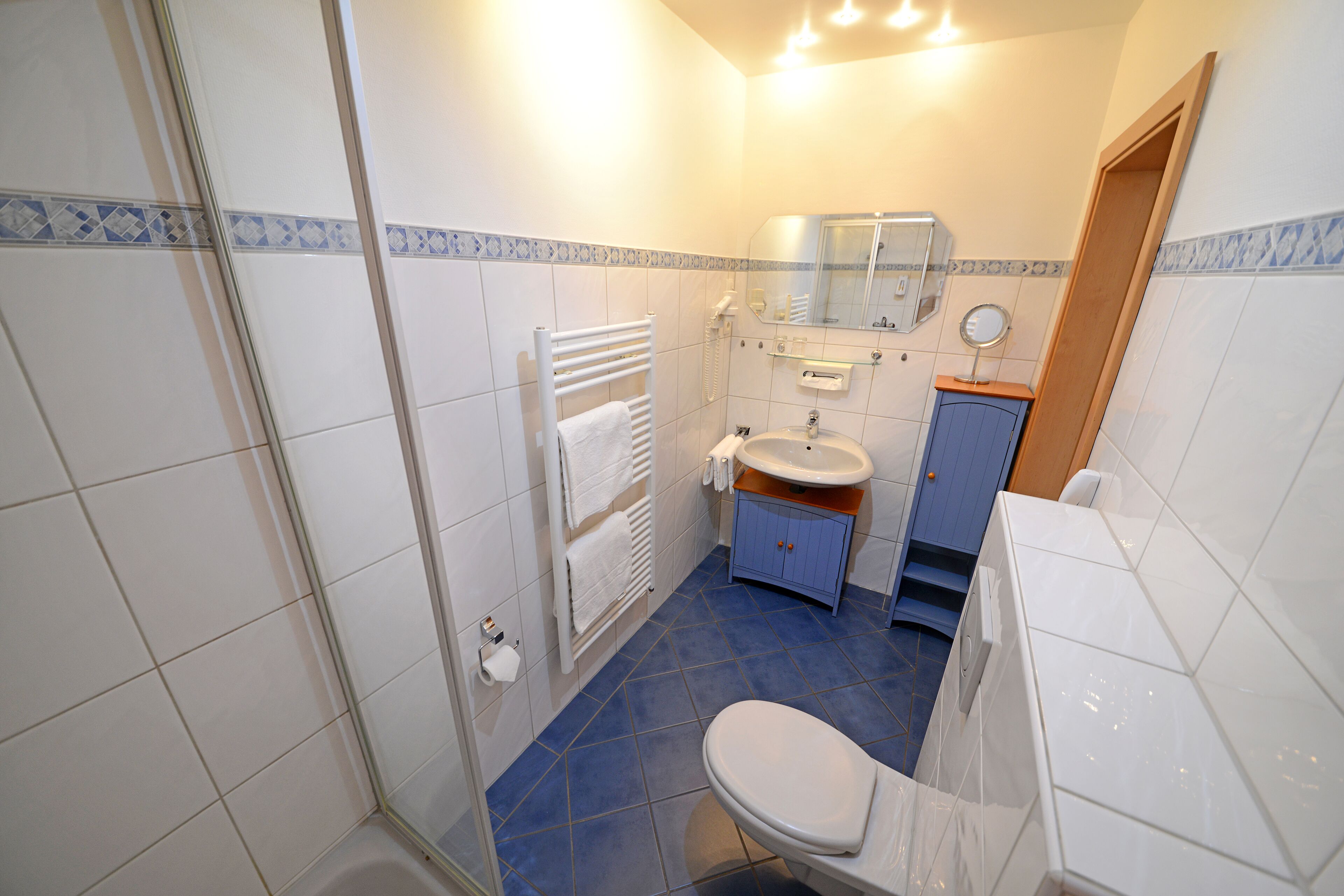 A bathroom with a toilet, sink, and mirror.