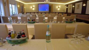 A conference room with multiple tables set up, each with bottles and glasses.