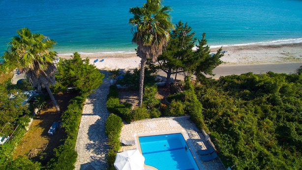 Vista aérea de un resort con piscina, playa y palmeras.