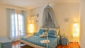 Un dormitorio con cama con dosel, una mesita de noche, una lámpara y una ventana con cortinas.