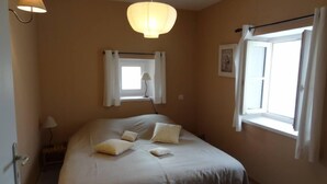 A bedroom with a large bed, a window with curtains, a wall-mounted lamp, and a small bedside table. - Drôme provençale quiet country house (Cléon-D'andran)