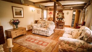 A cozy living room with floral-patterned sofas, a wooden coffee table, and a red patterned rug.