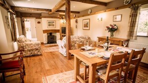 A cozy living room with a fireplace, wooden furniture, and a dining area with a table and chairs.