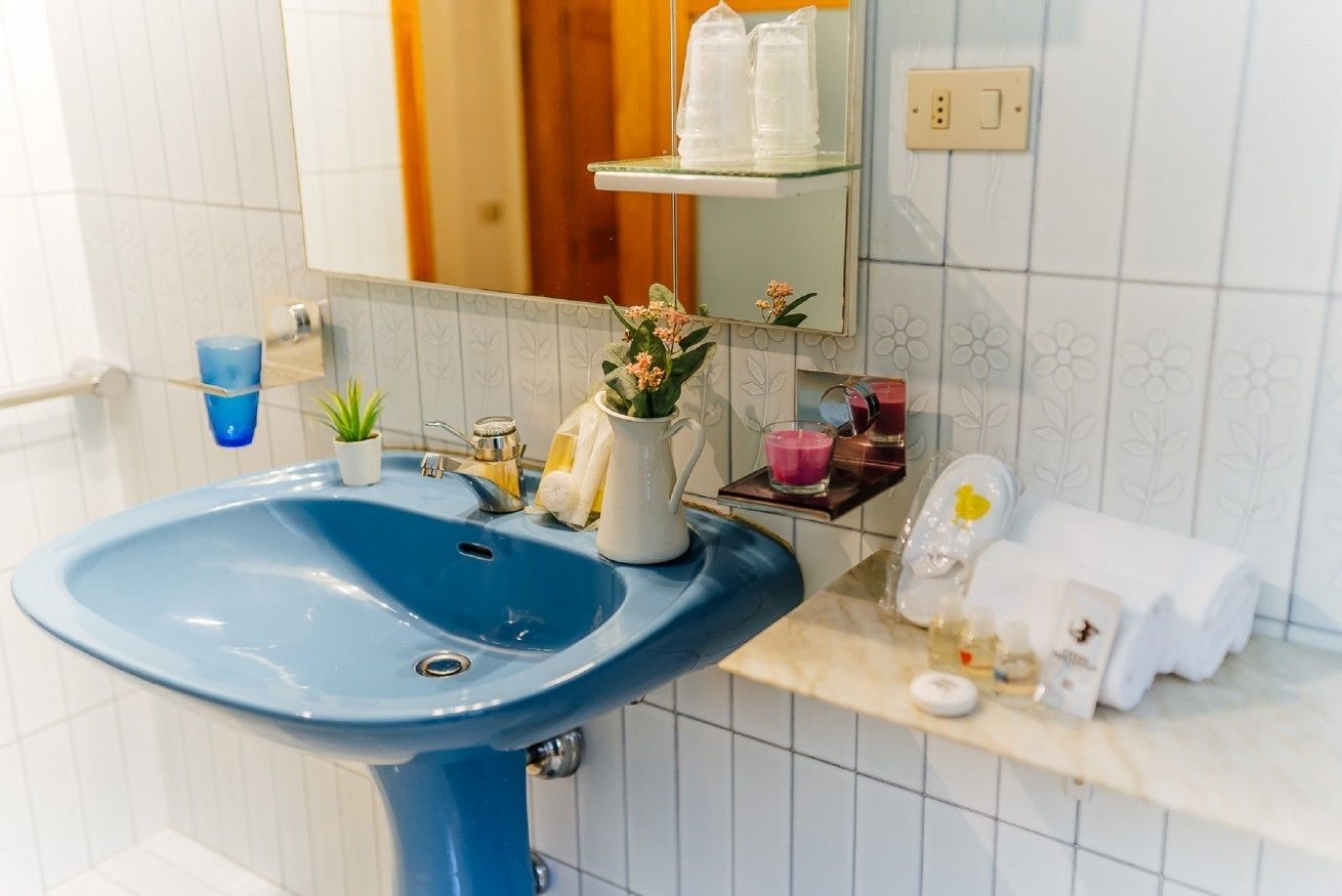 Ein Badezimmer mit einem blauen Waschbecken, einem Spiegel und einem Ablagebereich mit Pflegeprodukten.