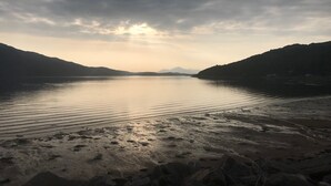 Un lac paisible, avec des montagnes en arrière-plan et un ciel nuageux.