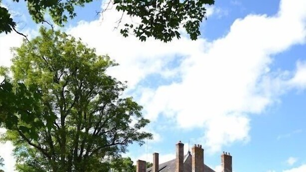 A large, historic building with multiple chimneys, surrounded by a well-maintained lawn and a large tree. - Manoir de Curty (Imphy)