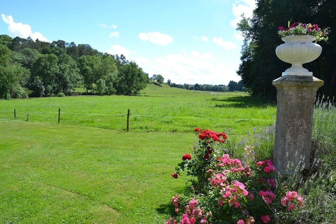 A grassy field with a stone pillar and flowers.
