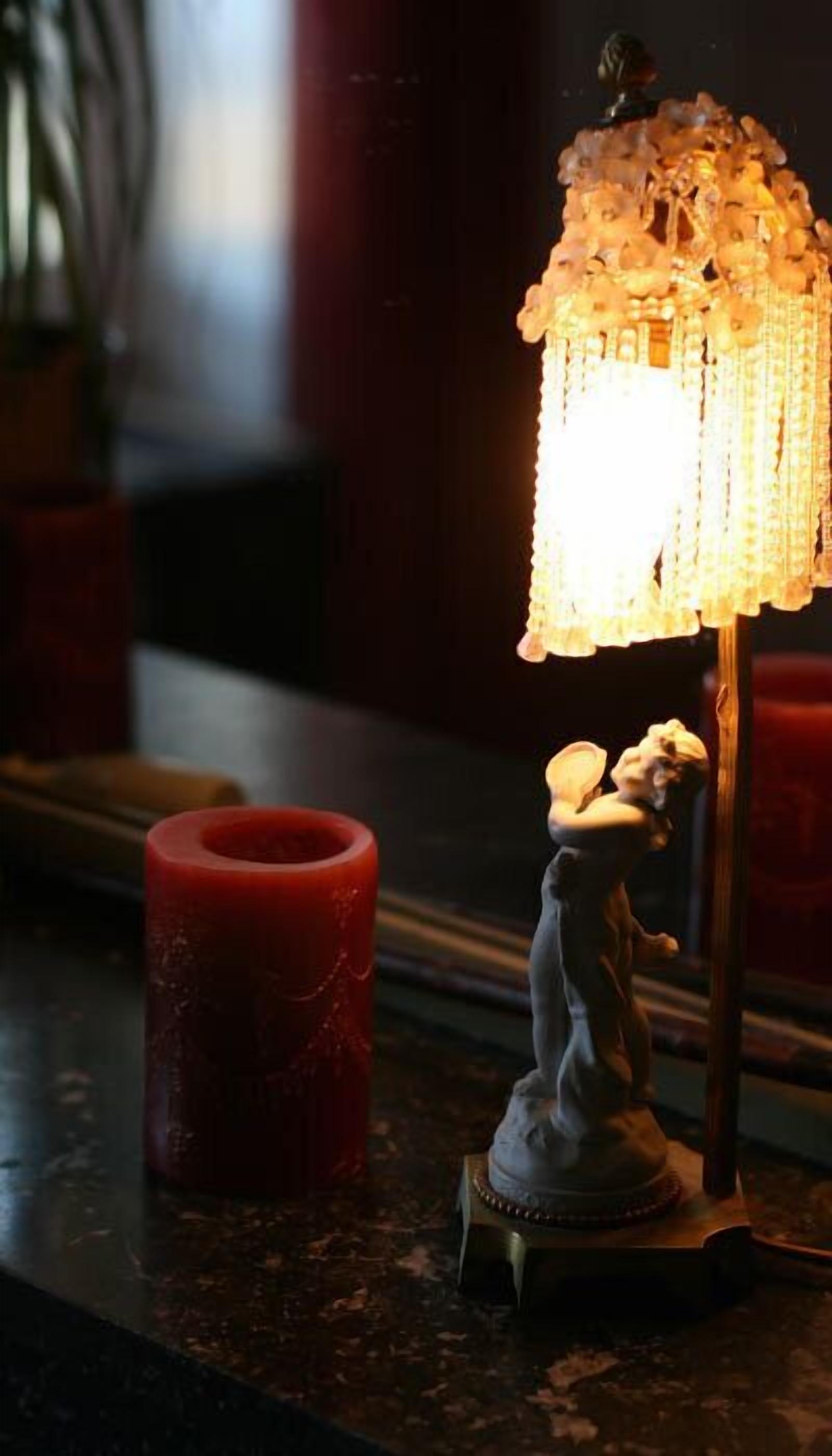 A table with a lit candle, a decorative lamp, and a small figurine.