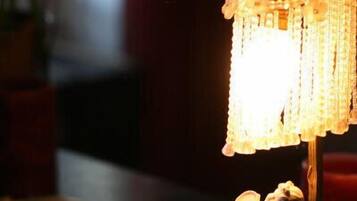 A table with a lit candle, a decorative lamp, and a small figurine.