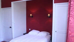 A hotel room with a bed, two doors, and wall-mounted lights. - Manoir de Curty (Imphy)