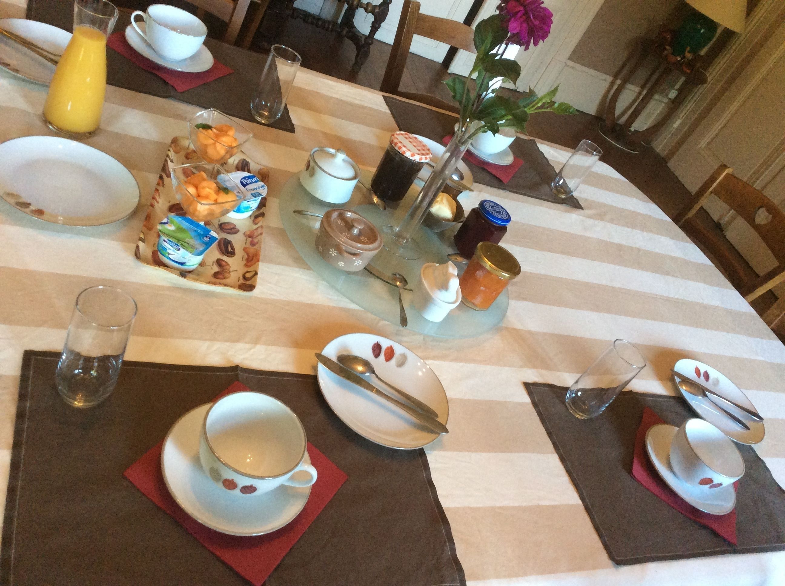 A breakfast table set with plates, cups, cutlery, and condiments.