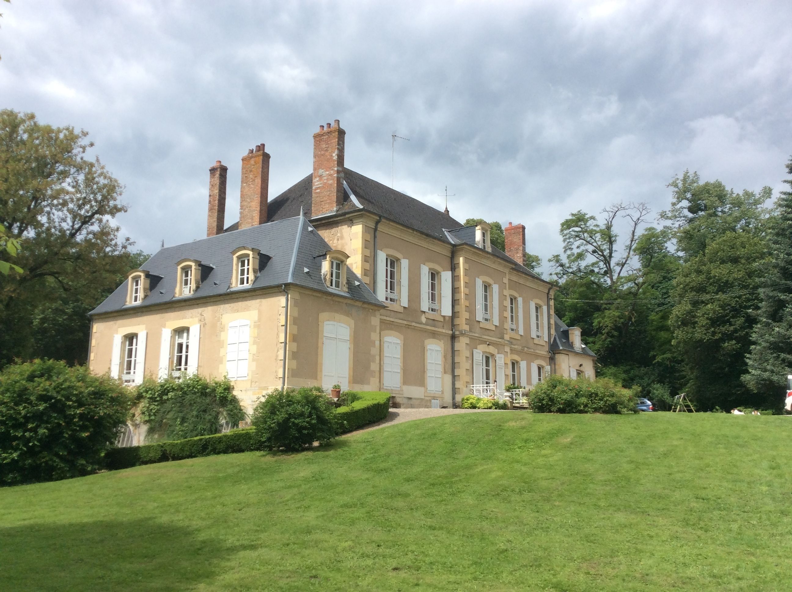 Un grand bâtiment à deux étages, doté de nombreuses cheminées, d’un toit en pente et d’une pelouse bien entretenue à l’avant.