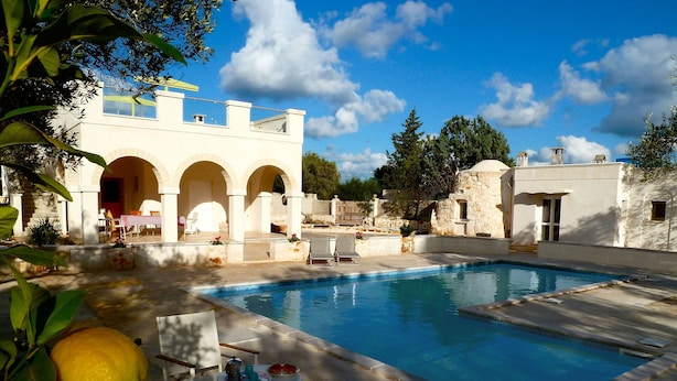 A pool area with a stone building, outdoor seating, and a table with lemons. - Beautiful Character Villa and Trullo in Ostuni Olive Grove with Private Pool (Ostuni 72017 (BR))