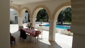 An outdoor patio with a pool, covered seating area, and a view of the pool. - Beautiful Character Villa and Trullo in Ostuni Olive Grove with Private Pool (Ostuni 72017 (BR))