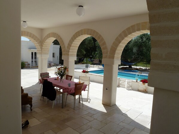 Eine Außenpatio mit Pool, überdachter Sitzbereich und Blick auf den Pool.