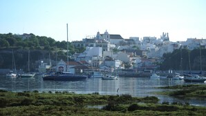 A coastal town with boats docked along the waterfront, buildings with varied architecture, and a hilly backdrop. - Beach villa with sea view roof terrace for the whole family (Alvor)