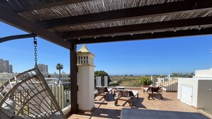 A rooftop terrace with a hanging chair, lounge chairs, and a view of the city and sea. - Beach villa with sea view roof terrace for the whole family (Alvor)