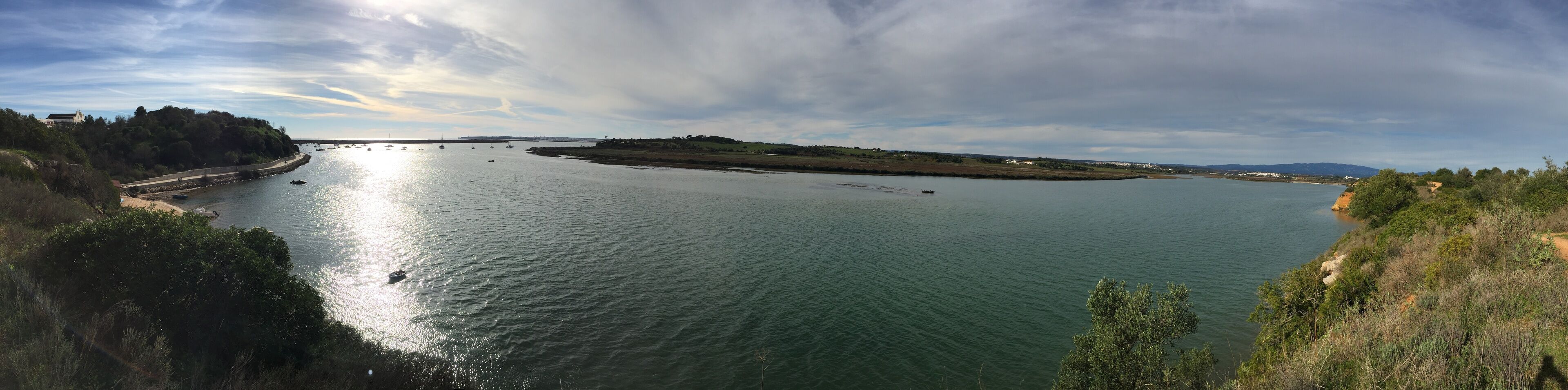 A wide river with boats, a bridge, and a hilly landscape.