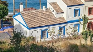 Ein Küstengebäude mit Ziegeldach, weißen Wänden und blauen Akzenten mit Blick auf das Meer.