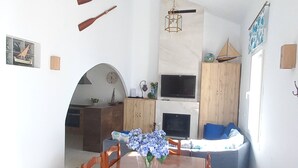 Ein geräumiger Essbereich mit Holztisch und Stühlen, einer Blumenvase und einer Küche im Hintergrund.