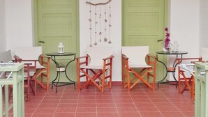 Un porxo cobert amb paviment de rajola, dues portes verdes i una decoració penjant.
