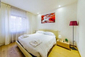 A hotel room with a large bed, a nightstand with a lamp, and a painting on the wall. - Welc-om Vittoria (Padova)