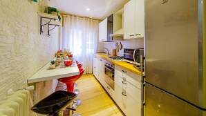 Une cuisine compacte équipée d’un réfrigérateur, d’un four à micro-ondes, d’un four traditionnel et d’un coin repas avec une table et des chaises.