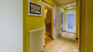 Un couloir avec un radiateur, un tableau encadré et une porte donnant sur une pièce.