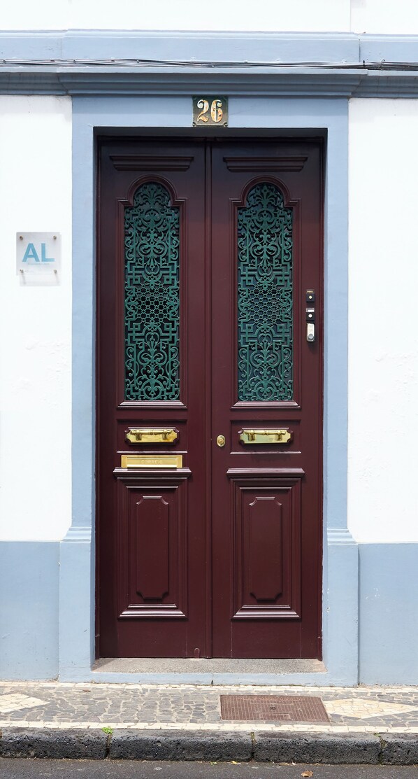 Una puerta doble con diseños intrincados, un buzón y una pequeña placa sobre la puerta.
