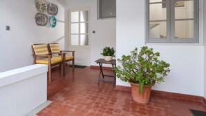 A room with a wooden bench, a potted plant, a door with frosted glass panels, and a window with a view of the interior.