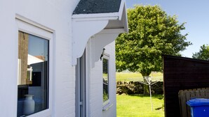 A white building with a window, a door, and a tree in the background.
