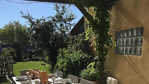 An outdoor dining area with a long table set for a meal, surrounded by chairs and equipped with various tableware and a fruit bowl. - Riverside House with pool, 4 bedrooms, 3 bathrooms, spacious with all ammenities (Mauzac-Et-Grand-Castang)