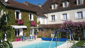 A swimming pool with lounge chairs and a small gazebo, surrounded by a garden with flowering plants and a building with ivy-covered walls. - Riverside House with pool, 4 bedrooms, 3 bathrooms, spacious with all ammenities (Mauzac-Et-Grand-Castang)