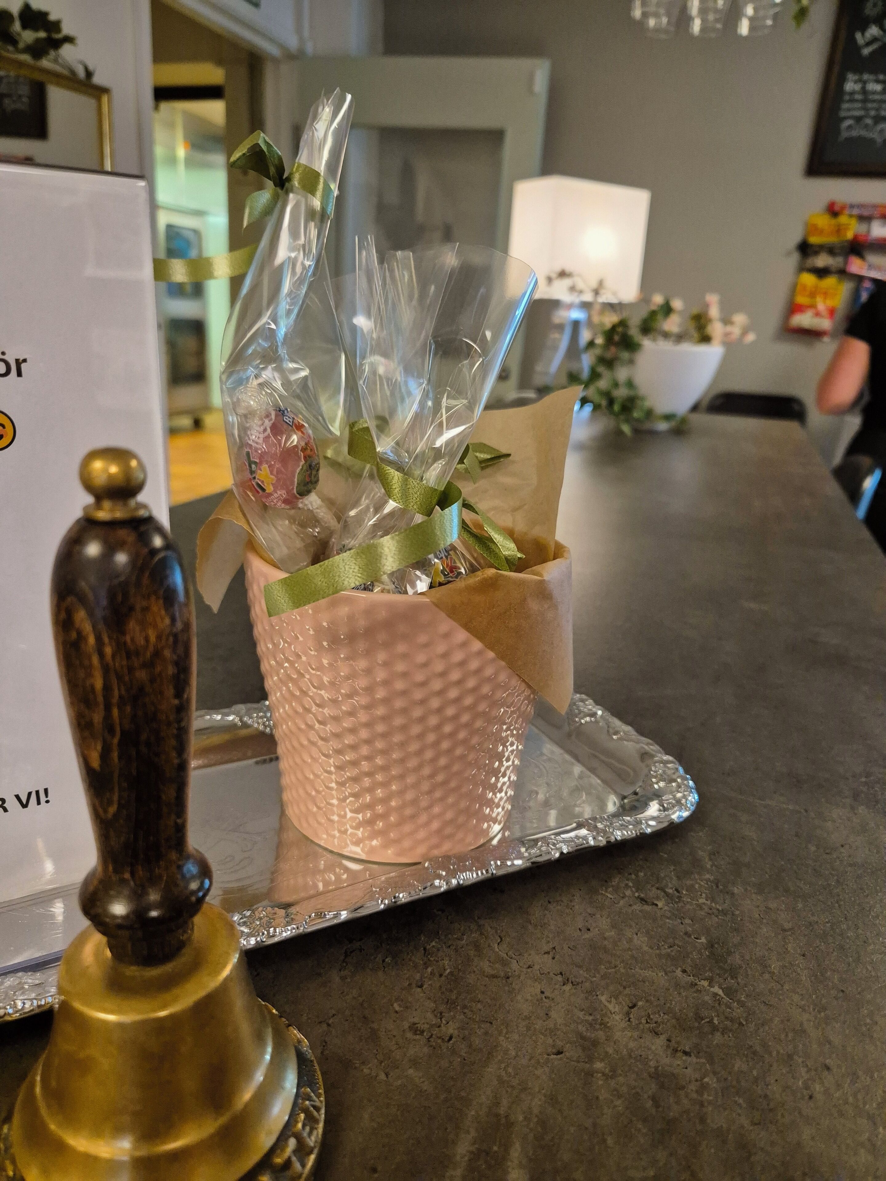Un objeto decorativo sobre una bandeja, posiblemente un regalo o adorno, con un recipiente rosa texturizado y un lazo verde.