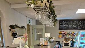 A modern reception area with a stone-textured counter, a bar stool, a decorative hanging light fixture, and a wall-mounted menu board. - Smålandsstenar hotell (Smalandsstenar)