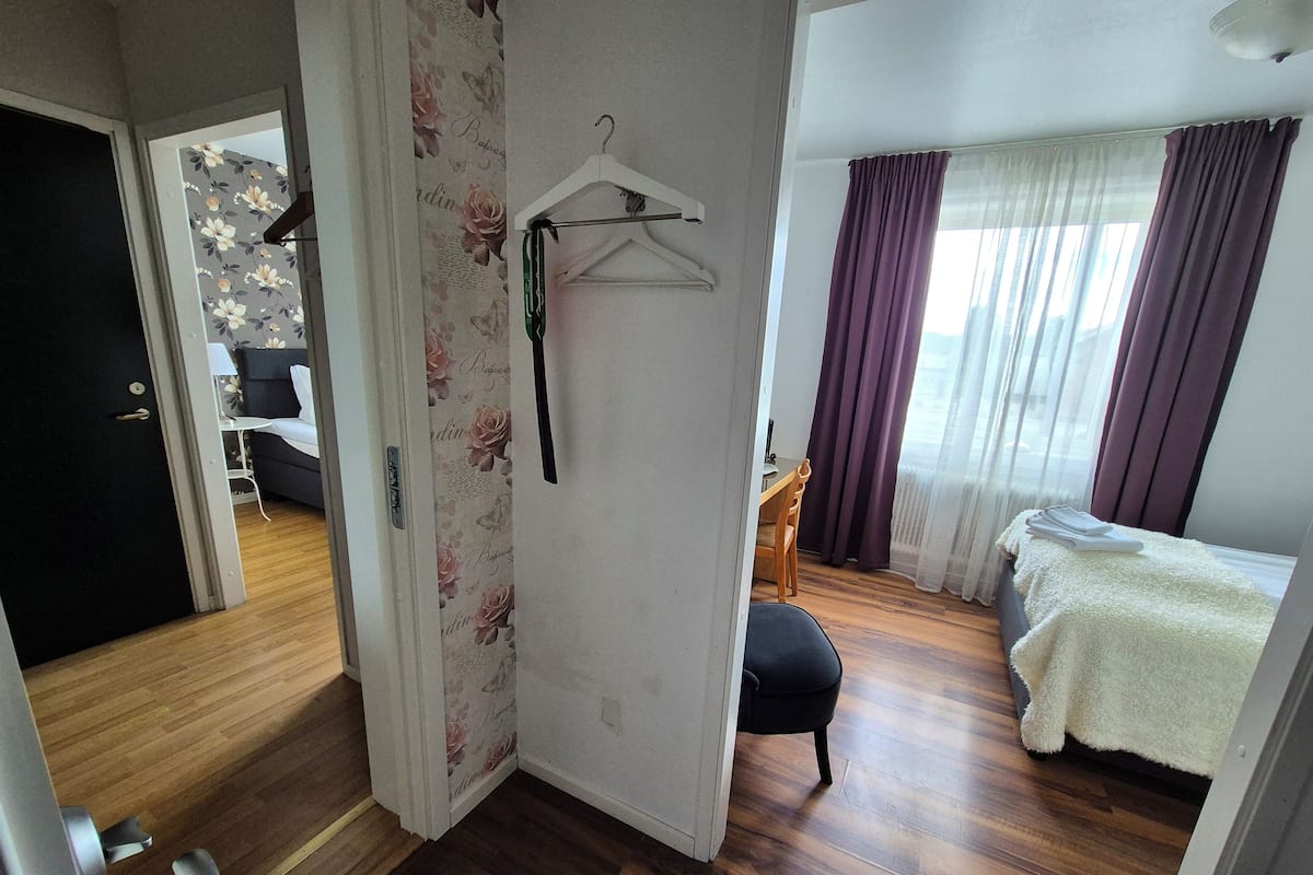 A bedroom with a bed, a chair, a desk, and a wardrobe.