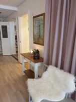Una habitación con un escritorio de madera, una silla blanca, un espejo y una puerta que da a un pasillo.