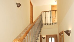 Una escalera con barandilla de madera y balaustradas de metal, que conduce a un segundo piso.