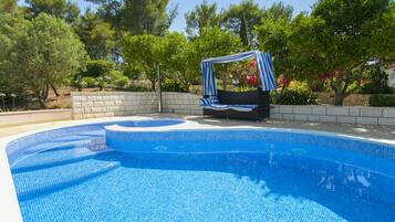 Relax by the pool surrounded by lush gardens and a shaded seating area.