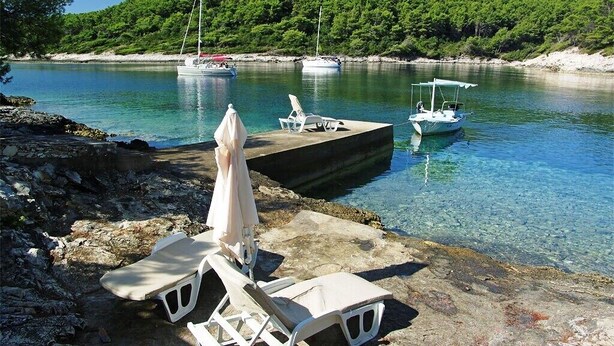 A marina with boats, clear water, and a dock with lounge chairs and umbrellas. - Luxury house with pool, direct beach & jetty access, stunning 270° sea view  (Vela Luka)
