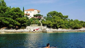 A man swimming in a clear blue sea with a house and trees in the background. - Luxury house with pool, direct beach & jetty access, stunning 270° sea view  (Vela Luka)