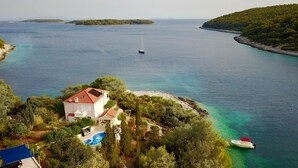A coastal property with a swimming pool, a boat, and a view of the sea and islands. - Luxury house with pool, direct beach & jetty access, stunning 270° sea view  (Vela Luka)