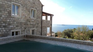 A stone building with a pool and a view of the sea. - Magnificent Newly-built Villa in Mlini with Private Pool and Near Beaches (20207 Mlini)