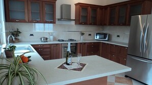 A modern kitchen with wooden cabinets, a stainless steel refrigerator, a microwave, and a central island with a sink and a potted plant. - Magnificent Newly-built Villa in Mlini with Private Pool and Near Beaches (20207 Mlini)