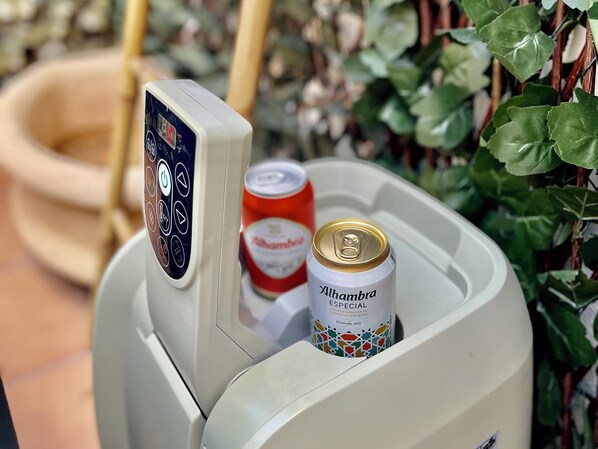 Un distributeur automatique contenant une canette de bière Alhambra et un bidon rouge.