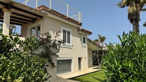 A two-story house with a balcony, a small garden, and a palm tree.