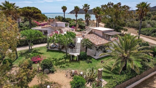 A Mediterranean-style villa with a spacious patio, a spiral staircase, and a view of the sea.