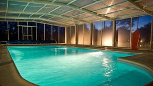 An indoor swimming pool with clear glass walls and a tiled floor.