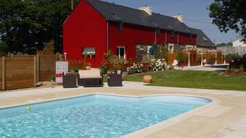 A red house with a swimming pool and outdoor furniture.