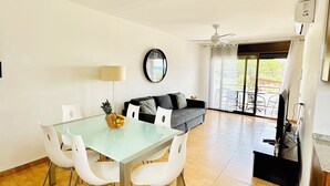 Uma sala de estar ampla com uma mesa de jantar, cadeiras brancas, um sofá e um ventilador de teto.